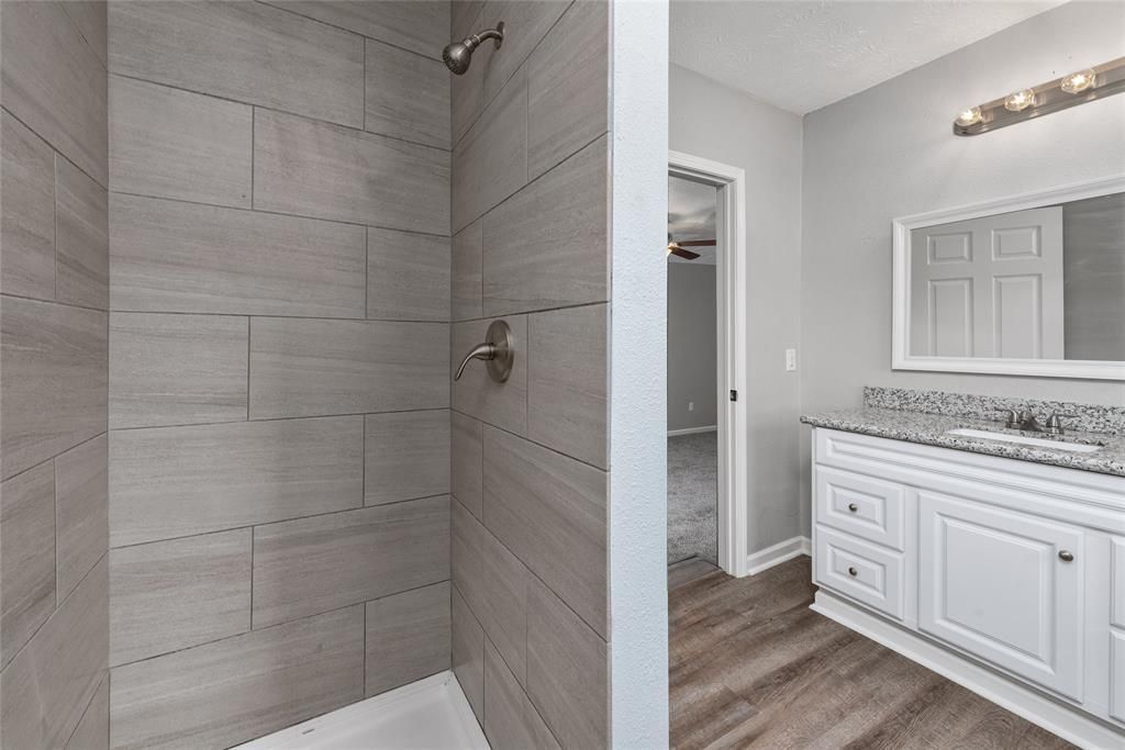 A bathroom with a walk in shower and a sink.