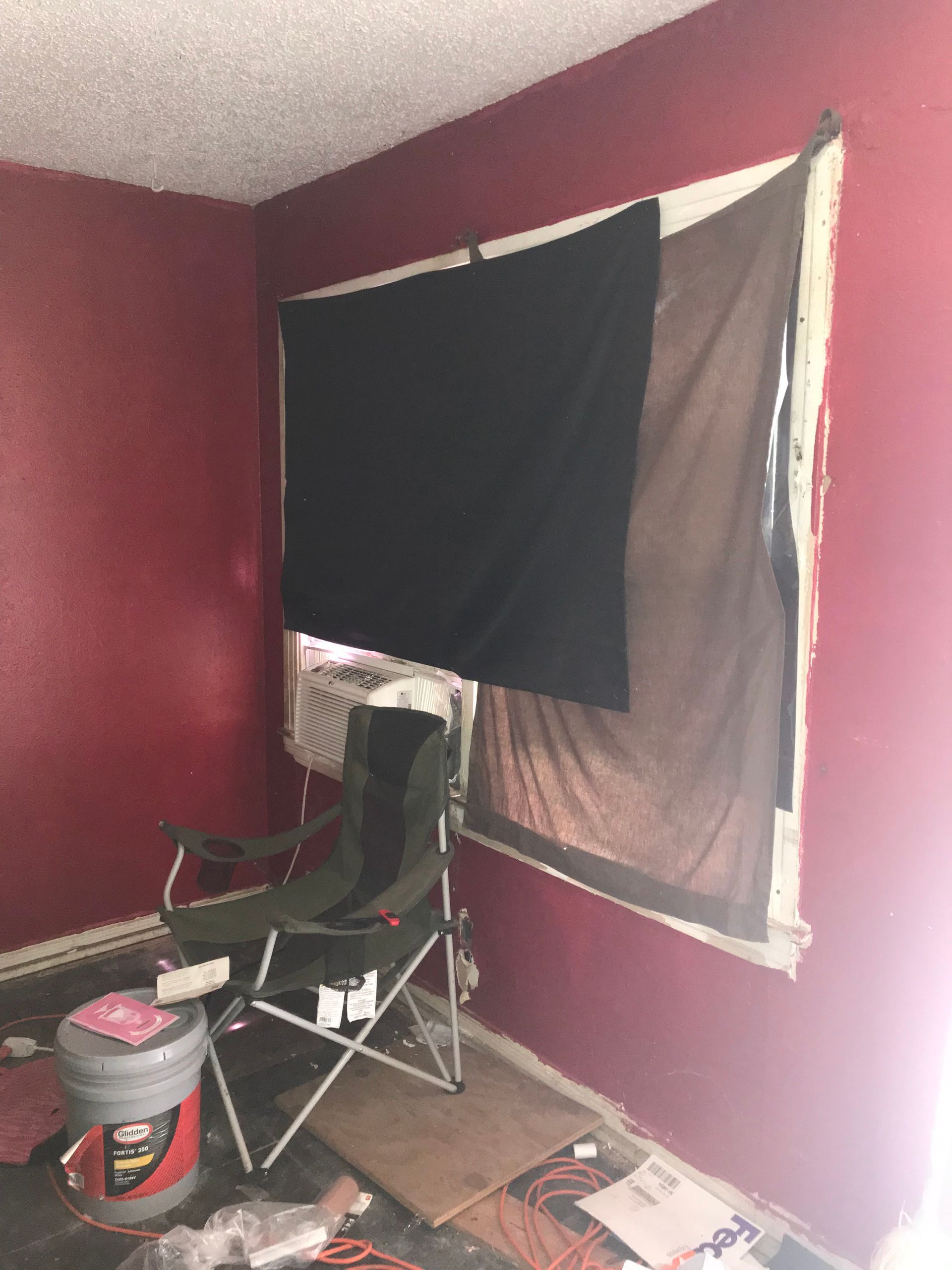 A room with red walls and a chair in front of a window.