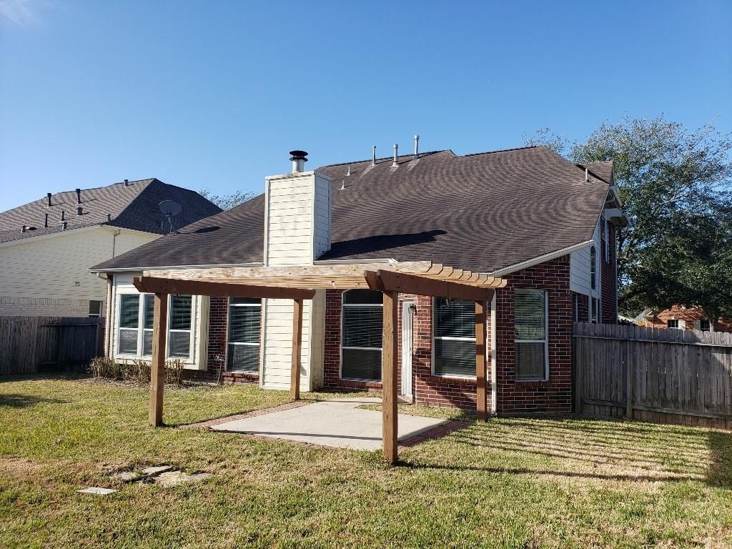 A brick house with a pergola in the backyard.