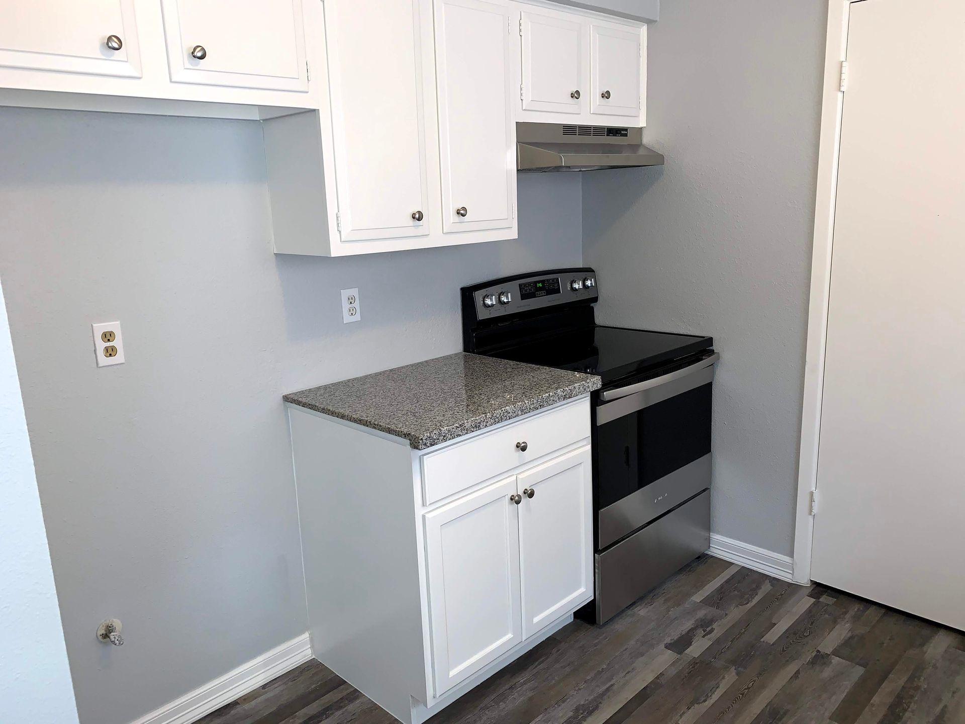 A kitchen with white cabinets , a stove , and a dishwasher.