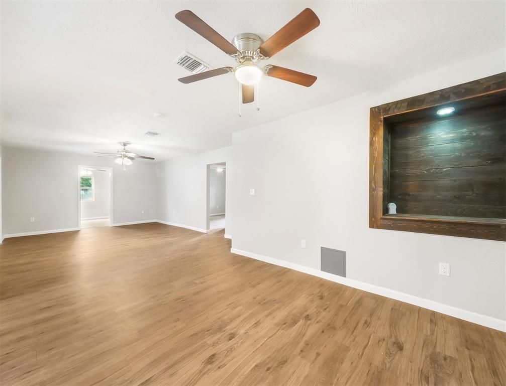 An empty living room with hardwood floors and a ceiling fan.