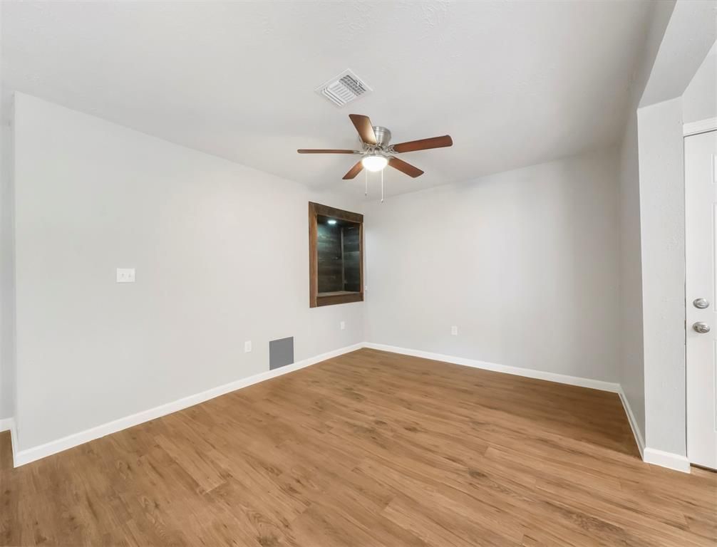 An empty room with hardwood floors and a ceiling fan.