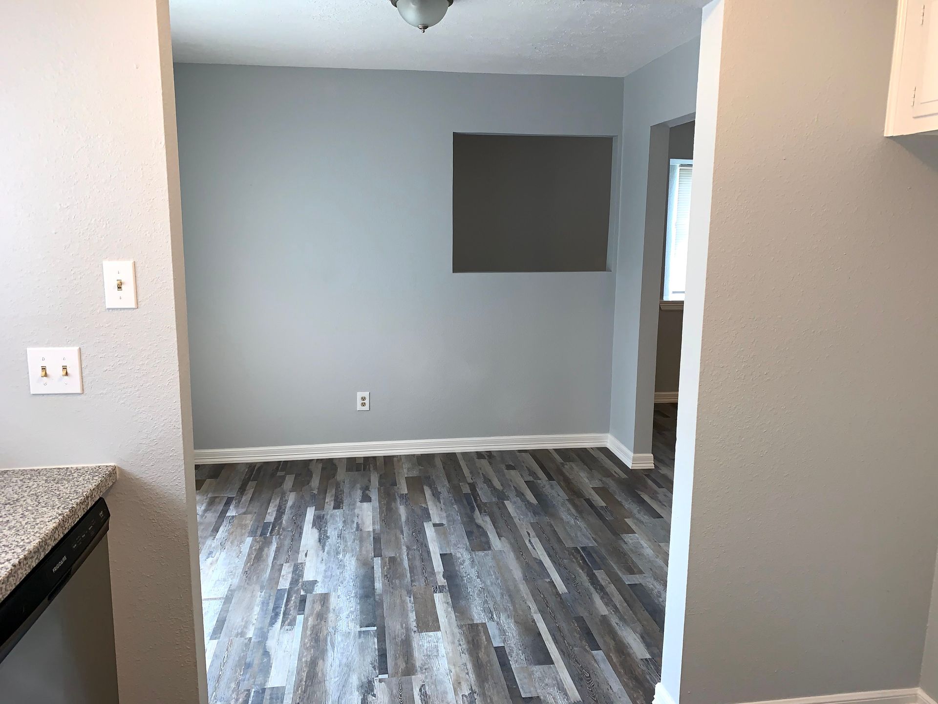 An empty room with a wooden floor and gray walls.