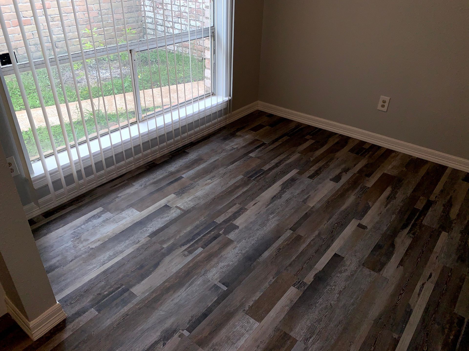 A room with a wooden floor and a sliding glass door.