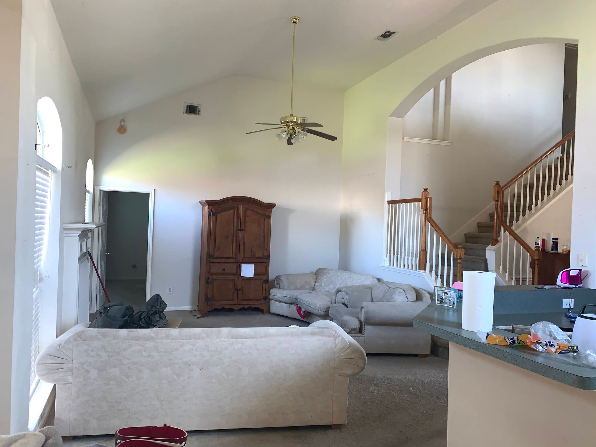 A living room with a couch , chairs and a ceiling fan.