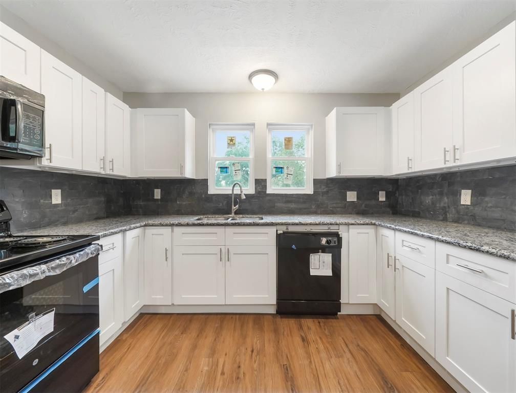 A kitchen with white cabinets and black appliances