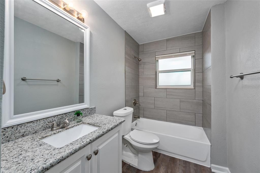 A bathroom with a sink , toilet , tub and mirror.