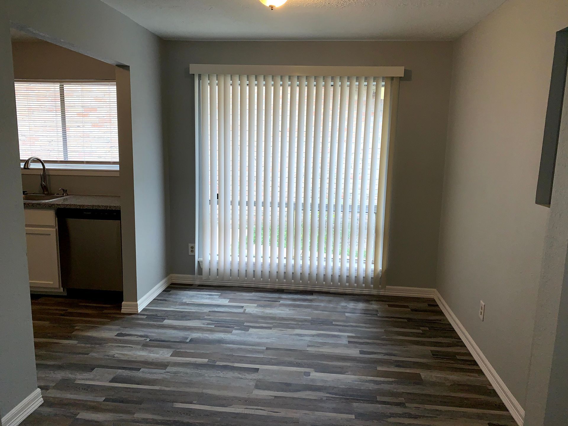 An empty living room with a sliding glass door and blinds.