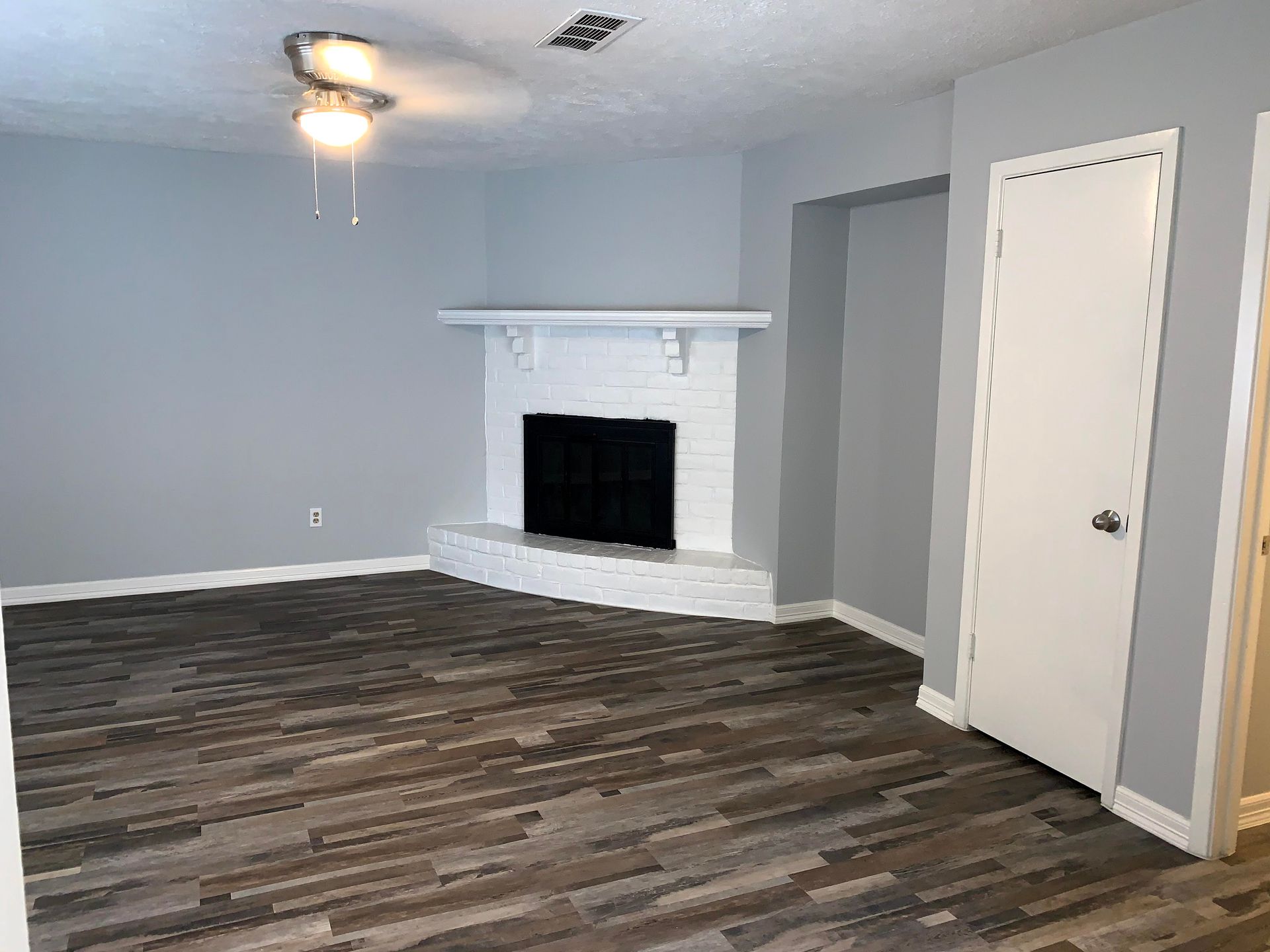 An empty living room with a fireplace and a ceiling fan.