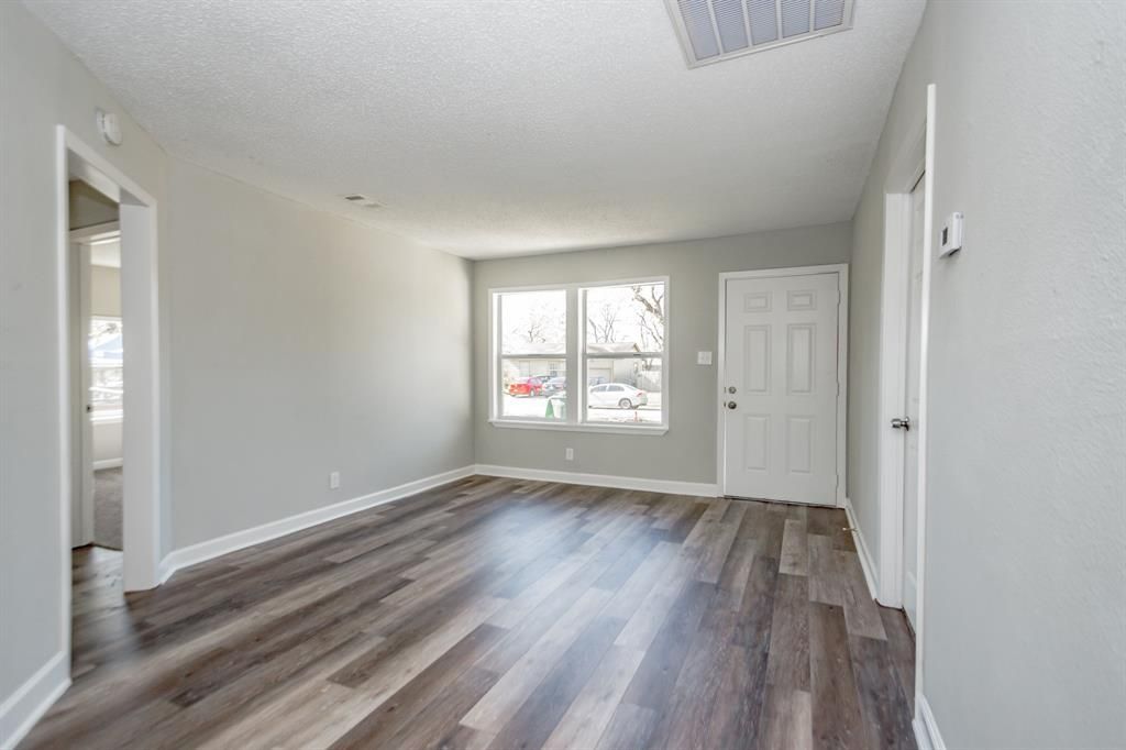 An empty living room with hardwood floors and a door.