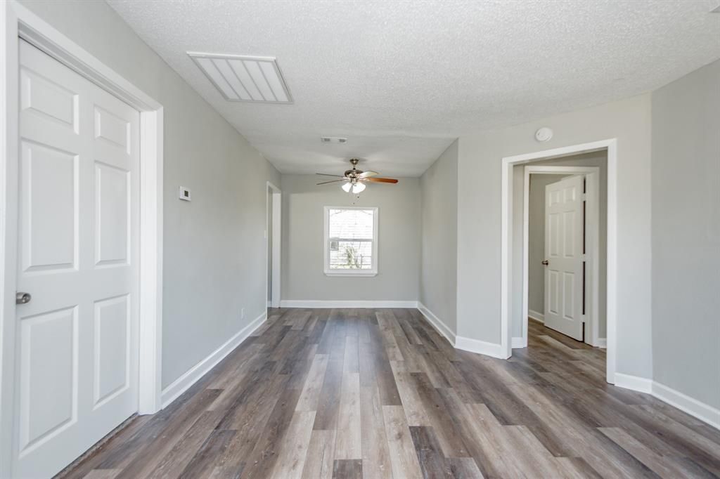 An empty living room with hardwood floors and a ceiling fan.