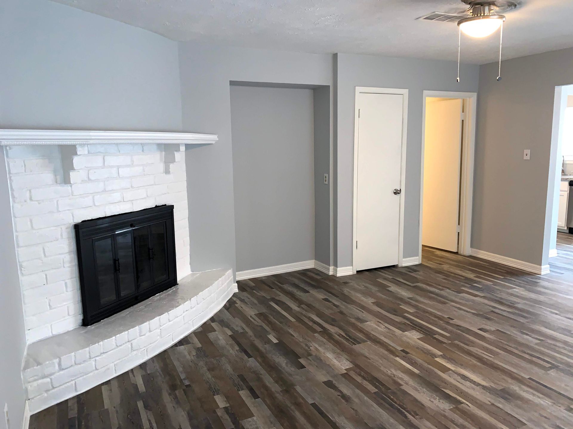 An empty living room with a fireplace and hardwood floors.