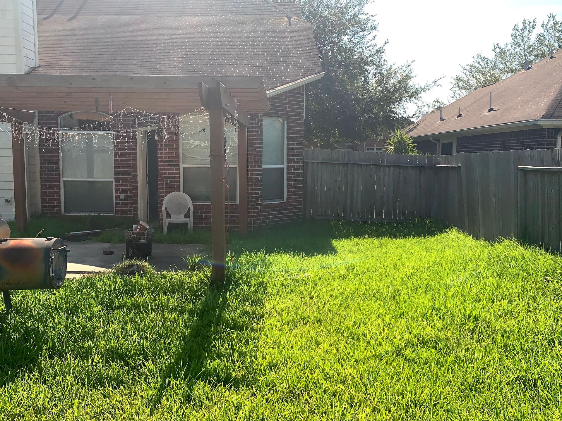 The backyard of a house with a pergola and a grill