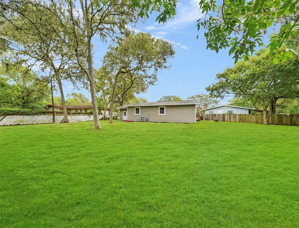 A house is sitting in the middle of a lush green field surrounded by trees.