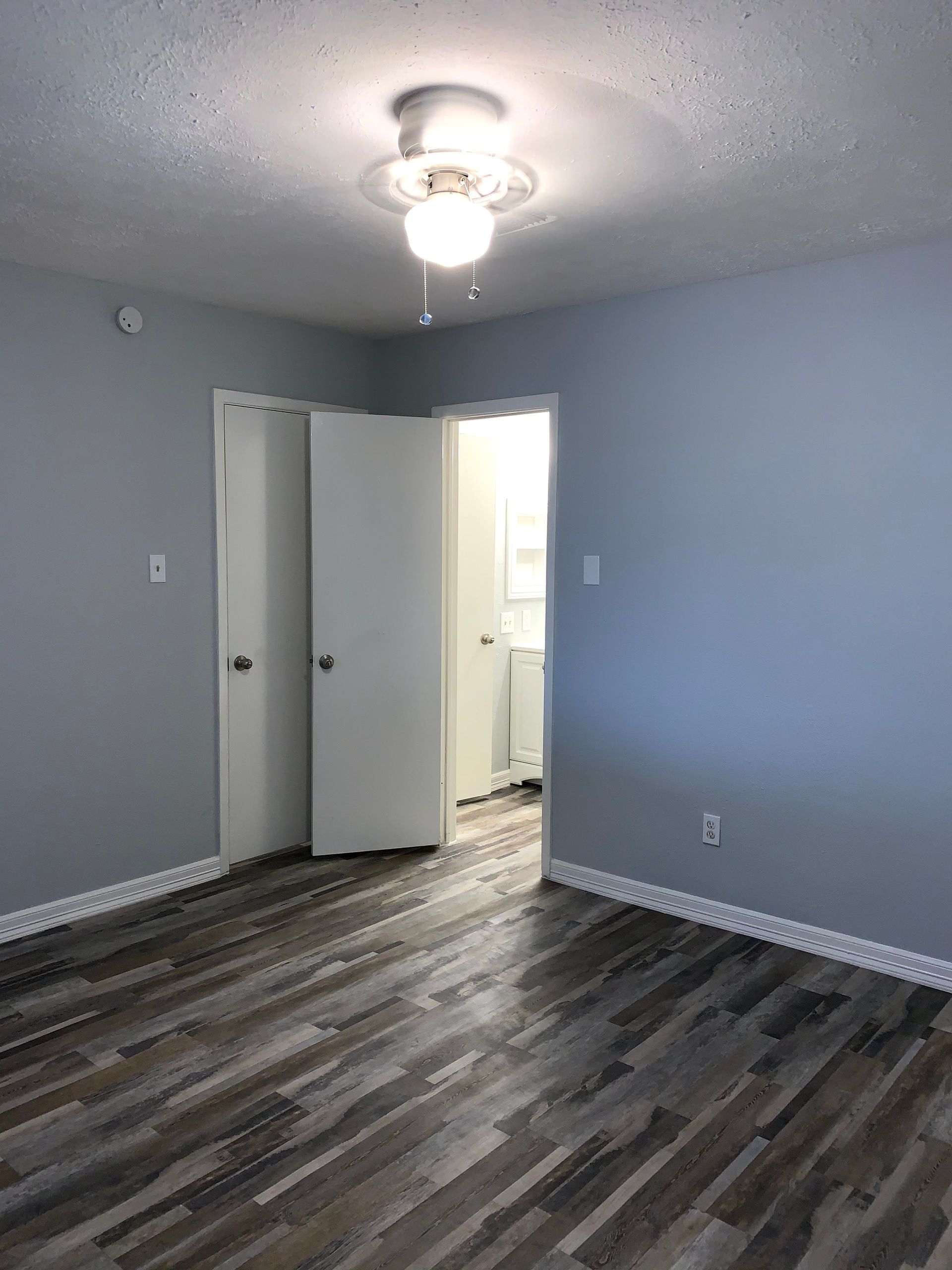 An empty bedroom with hardwood floors and a ceiling fan.