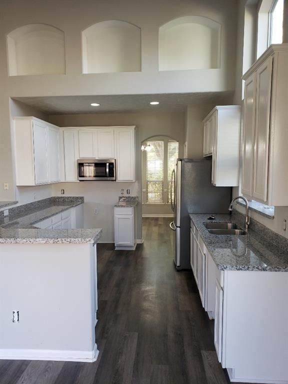 An empty kitchen with white cabinets and granite counter tops.