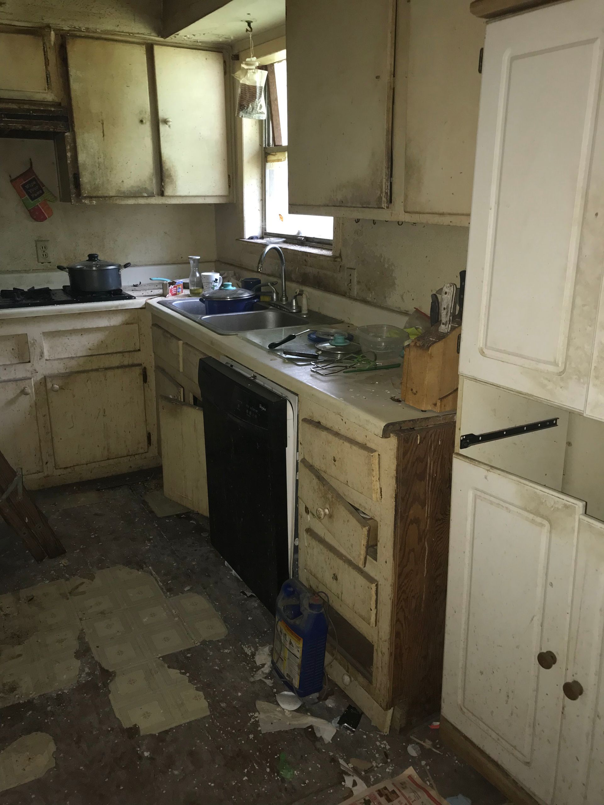 A kitchen with white cabinets and a black dishwasher