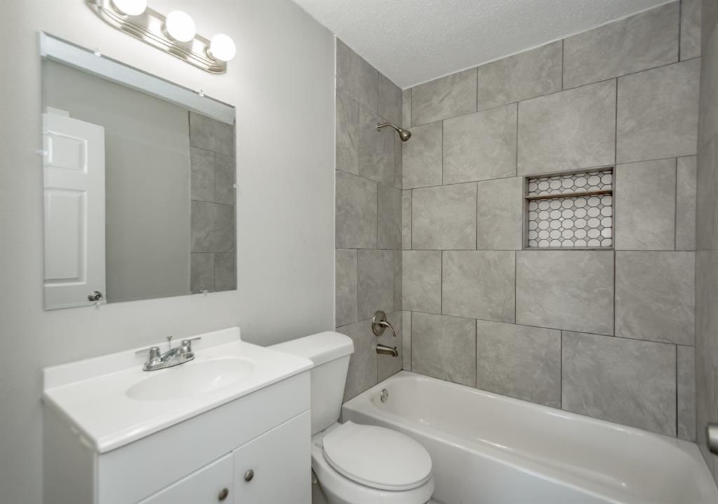 A bathroom with a toilet , sink , tub and mirror.