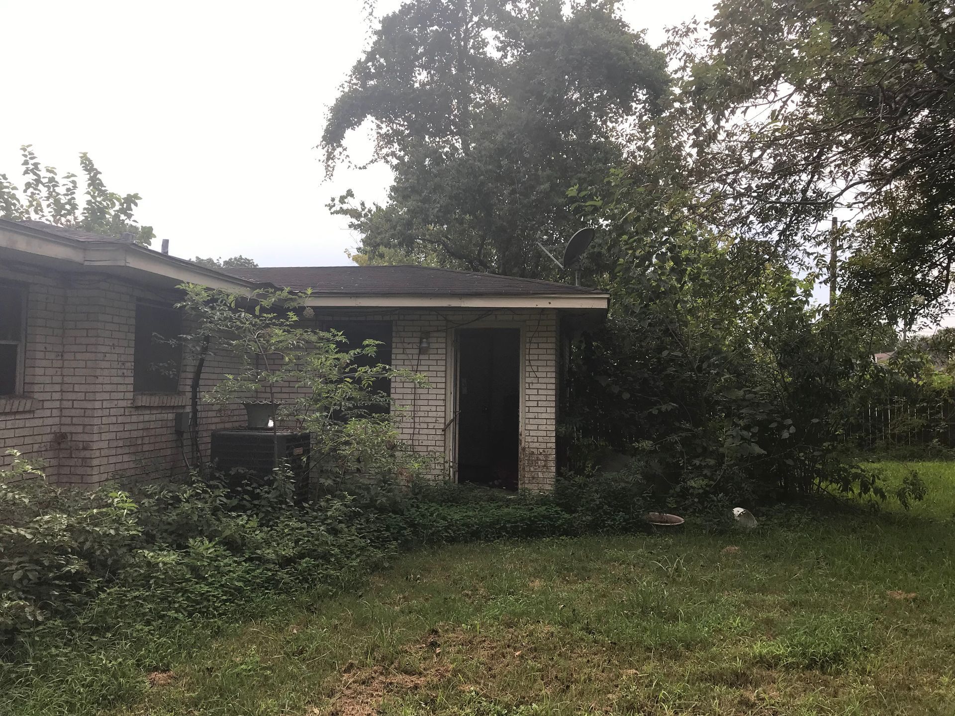 A brick house with a lot of trees in front of it.