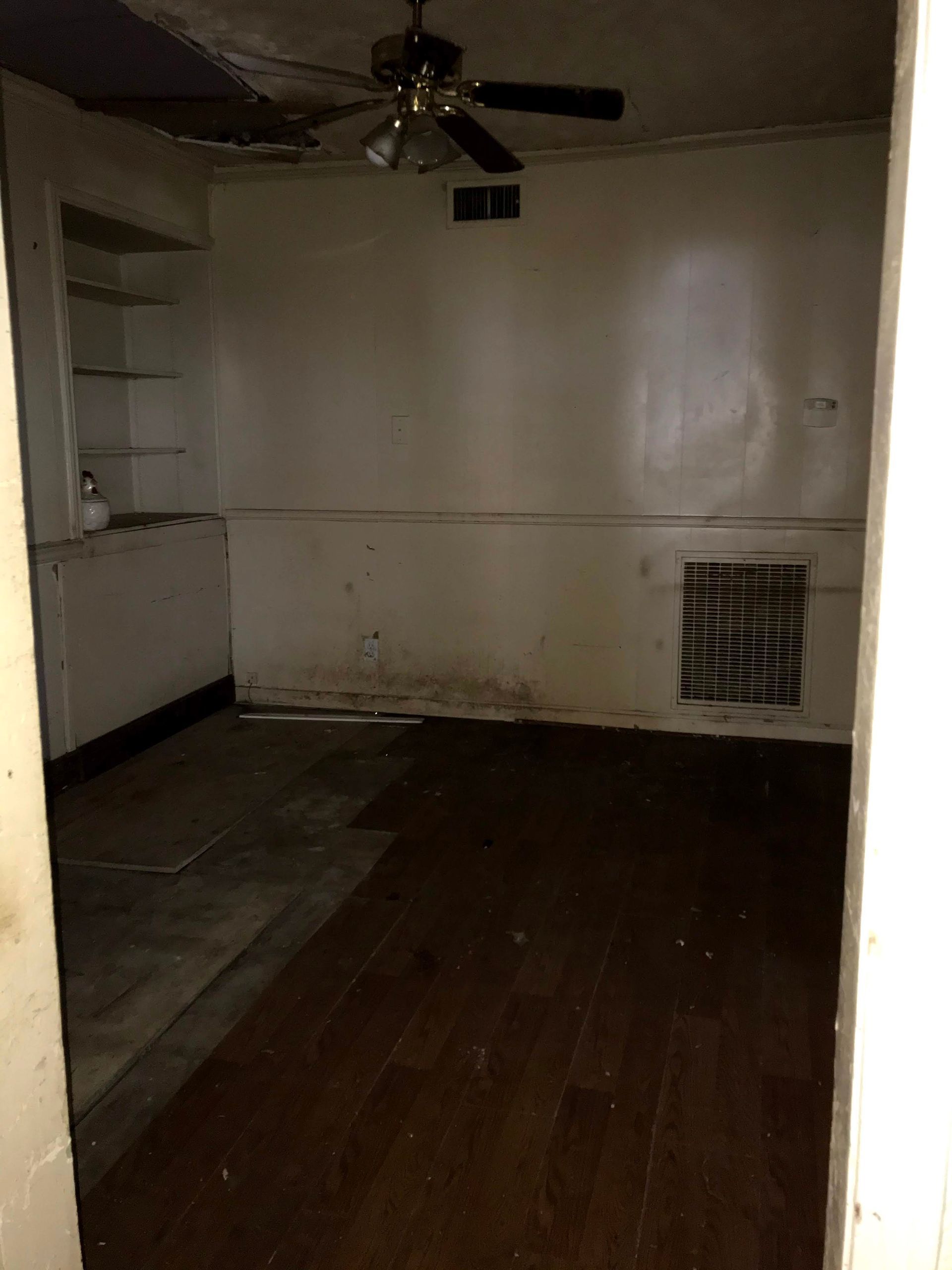 An empty room with a ceiling fan and wooden floors.