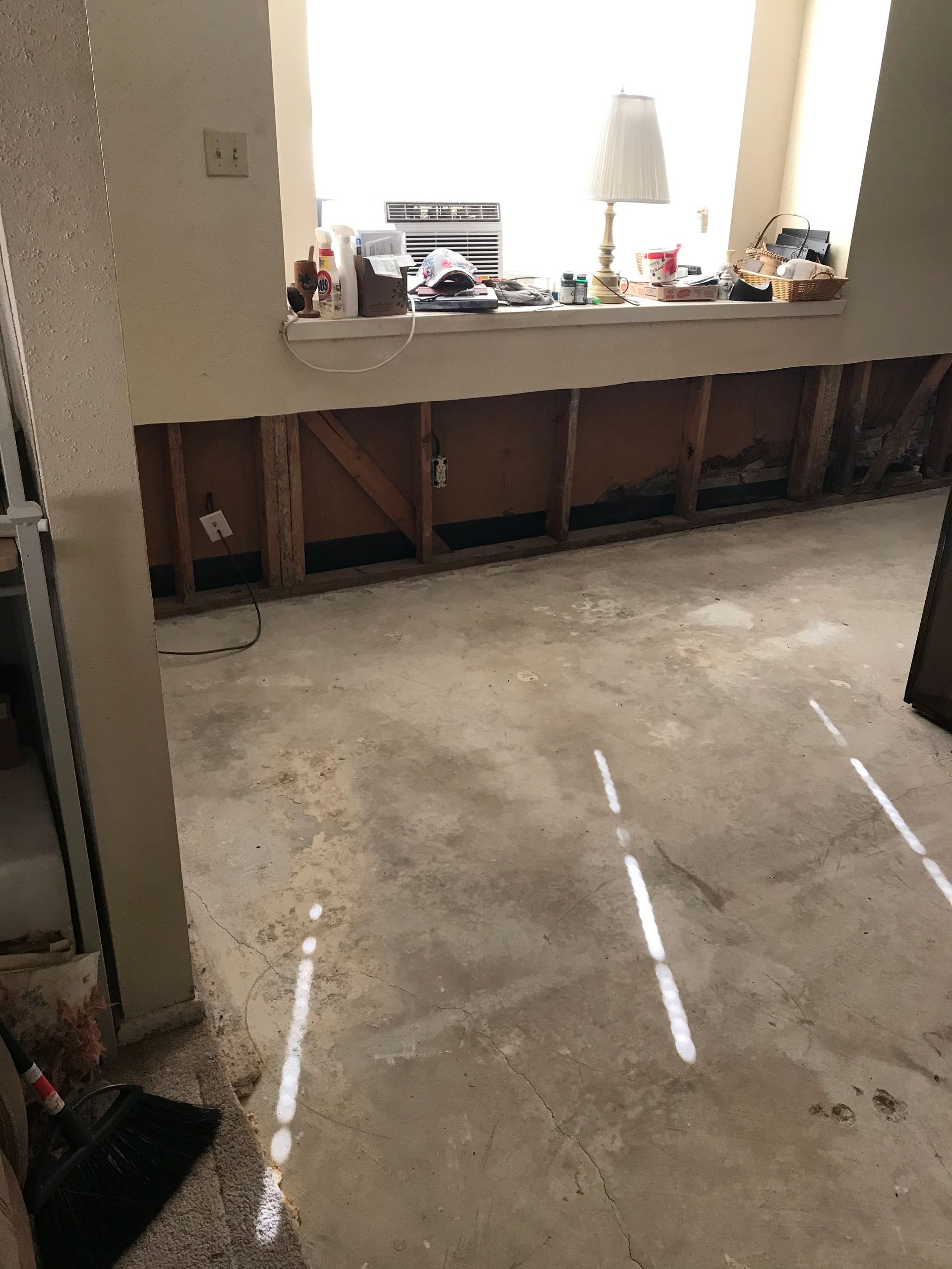 A room with a window and a broom on the floor.