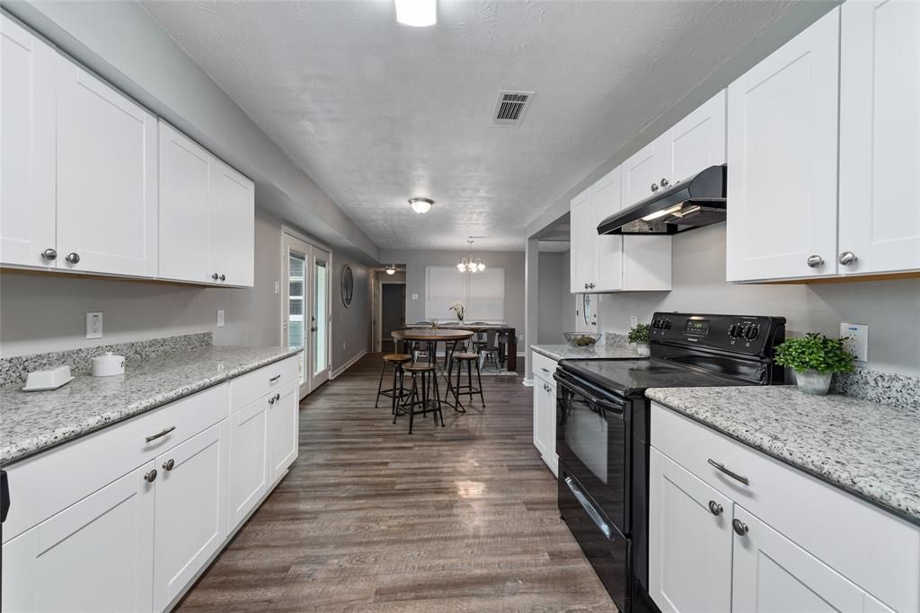 A kitchen with white cabinets , granite counter tops , and black appliances.