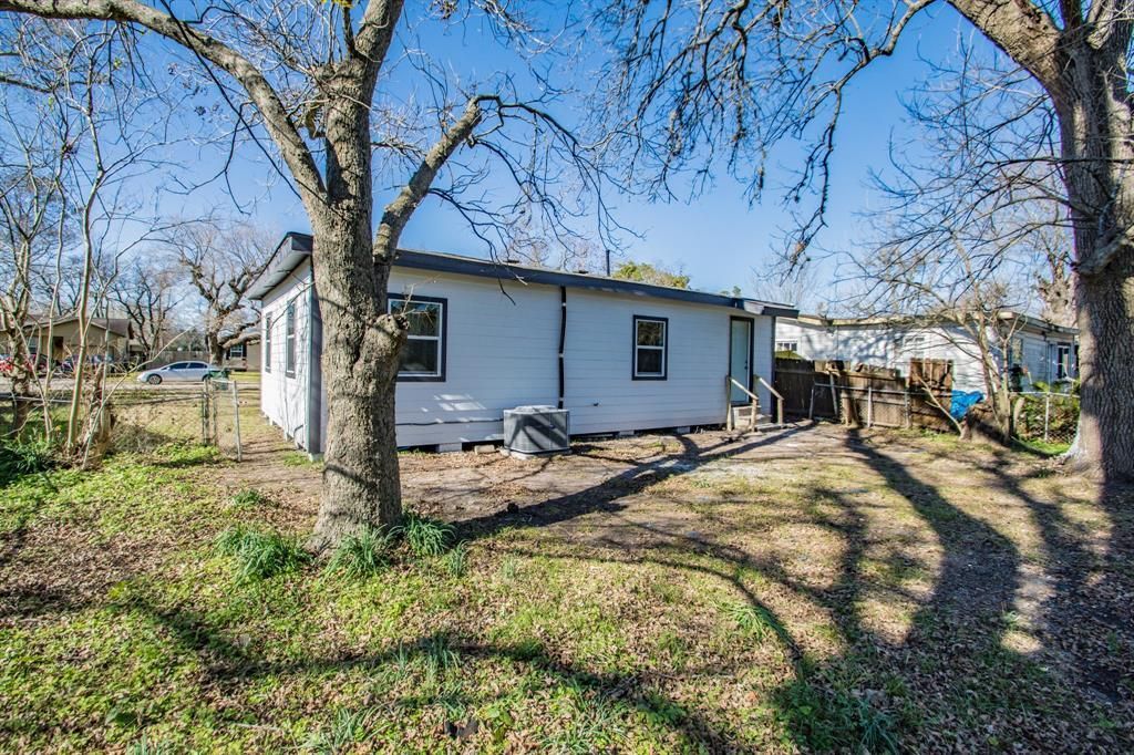 A white mobile home is sitting in the middle of a field surrounded by trees.