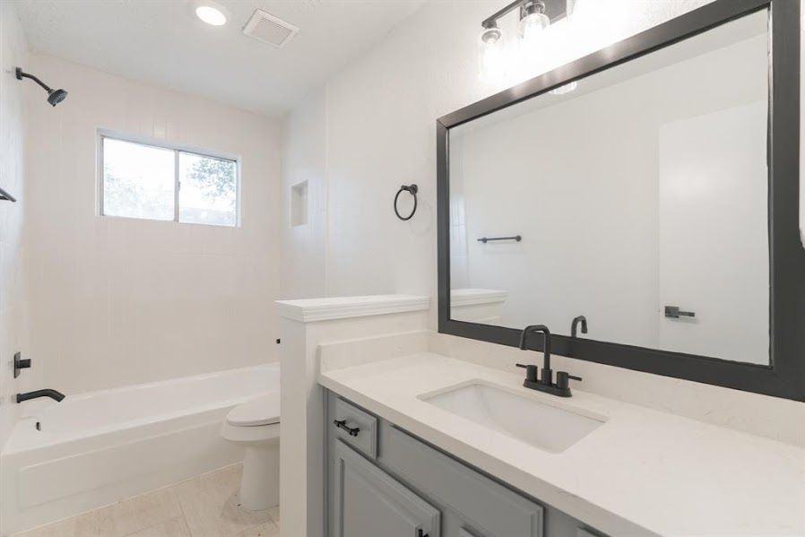 A bathroom with a sink , toilet , shower and mirror.