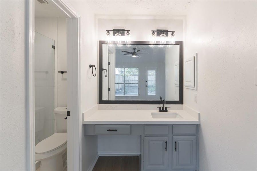 A bathroom with a sink , toilet and mirror.