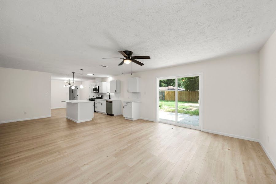 An empty living room with hardwood floors and a ceiling fan.