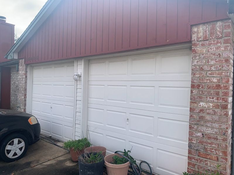 A car is parked in front of a garage door.