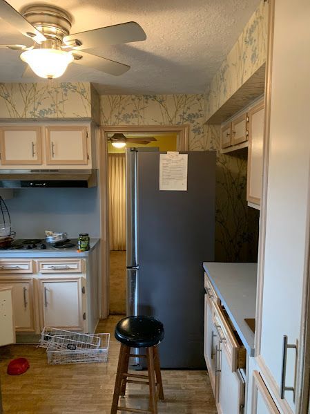 A kitchen with a refrigerator and a ceiling fan.