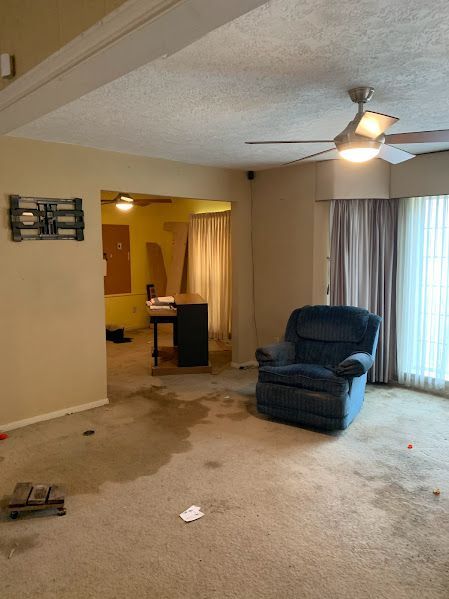 A living room with a blue chair and a ceiling fan.
