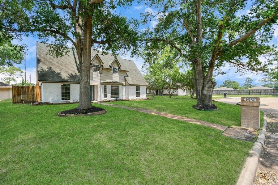 A large white house with a lush green lawn and trees in front of it.