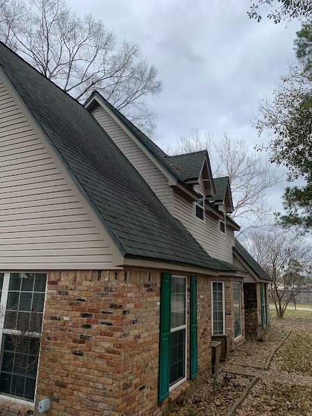 A brick house with a green roof and white siding.