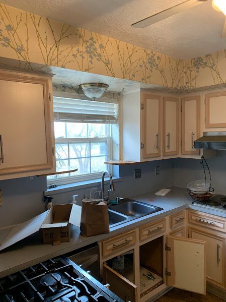 A kitchen with a stove , sink , cabinets and a window.