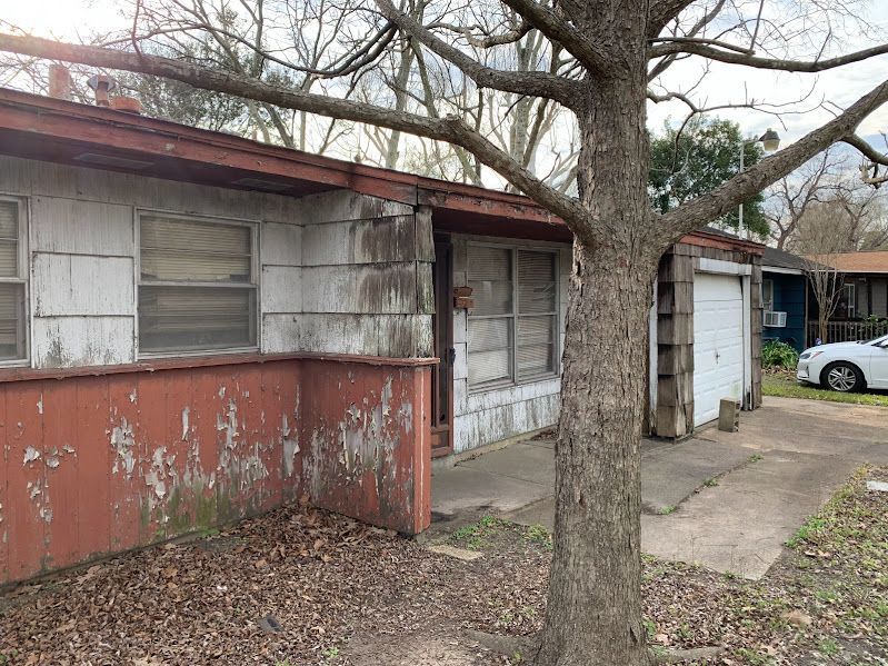 An old house with a tree in front of it and a car parked in front of it.