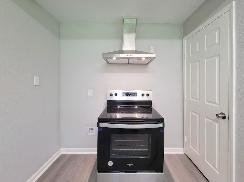 A kitchen with a stove , oven , and hood.