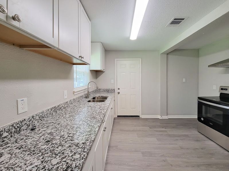 A kitchen with granite counter tops , stainless steel appliances , and white cabinets.
