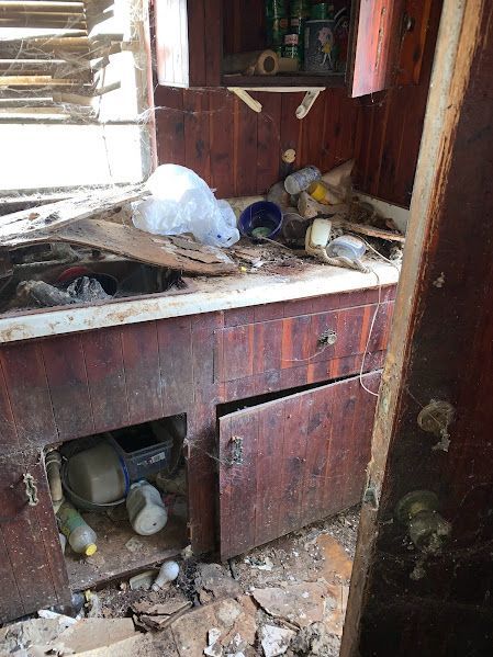 A kitchen with a sink , cabinets , and trash on the floor.