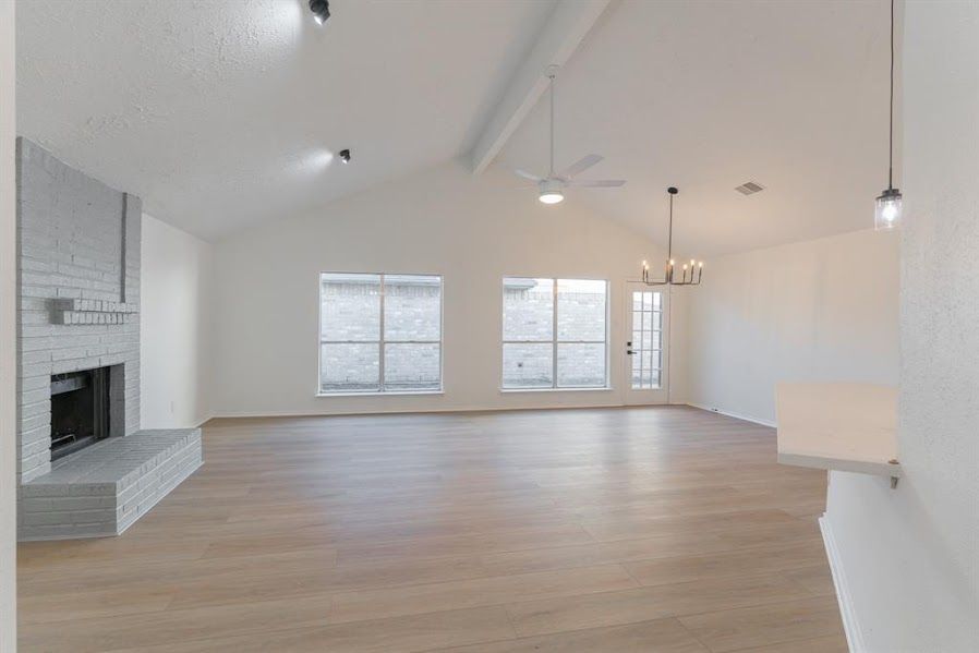 An empty living room with hardwood floors and a fireplace.