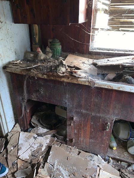 A messy room with a wooden table and a window.