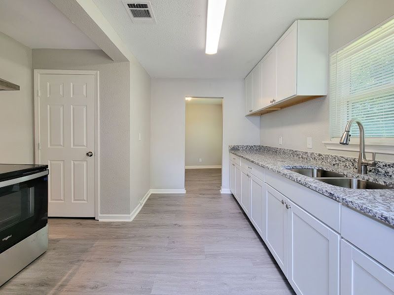 An empty kitchen with white cabinets and granite counter tops