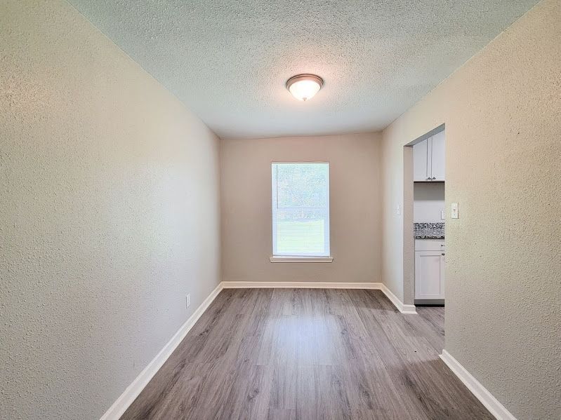 An empty living room with hardwood floors and a window.