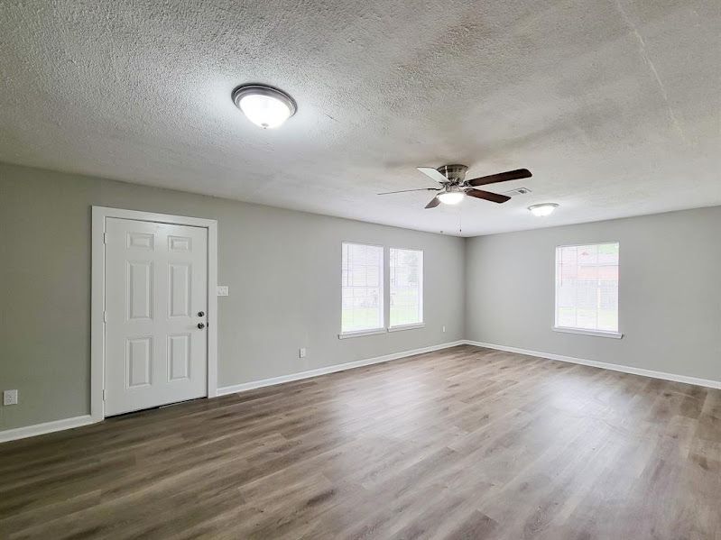 An empty living room with hardwood floors and a ceiling fan.