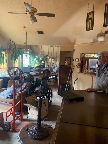 A man is standing in a living room with a ceiling fan.