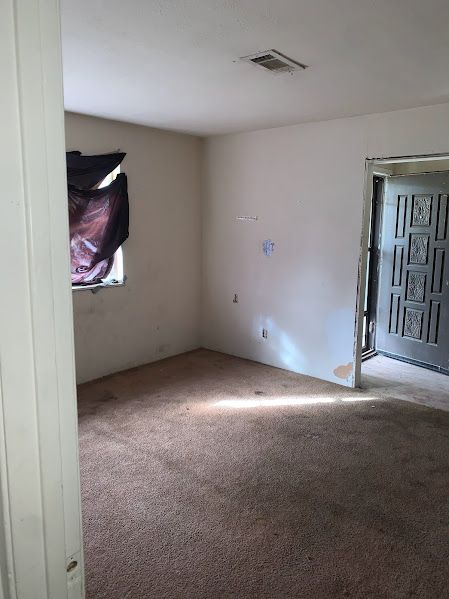 An empty room with a carpeted floor and a window.