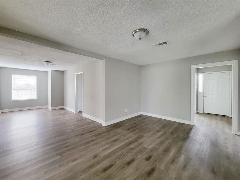 An empty living room with hardwood floors and a window.