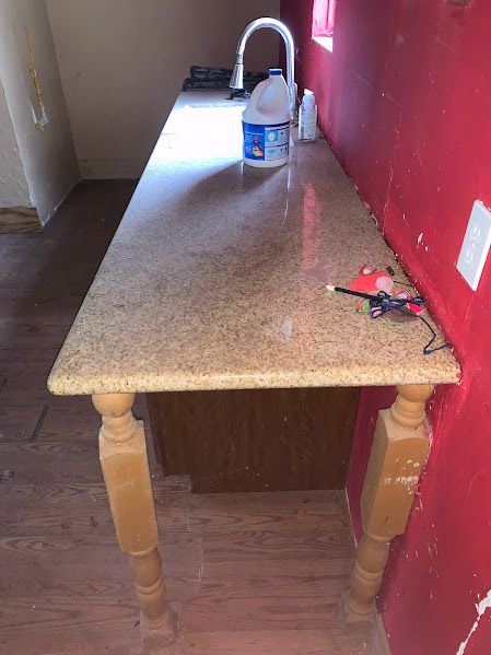 A kitchen counter with a bottle of bleach on it.