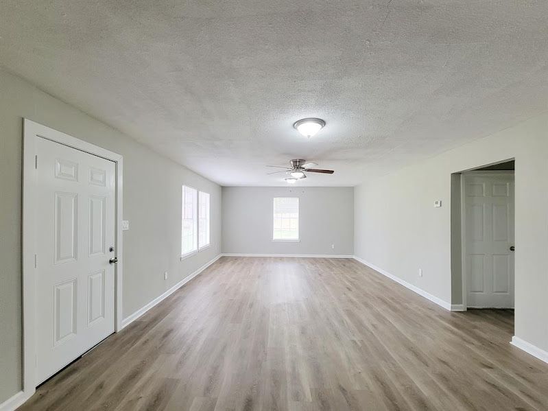 An empty living room with hardwood floors and a ceiling fan.